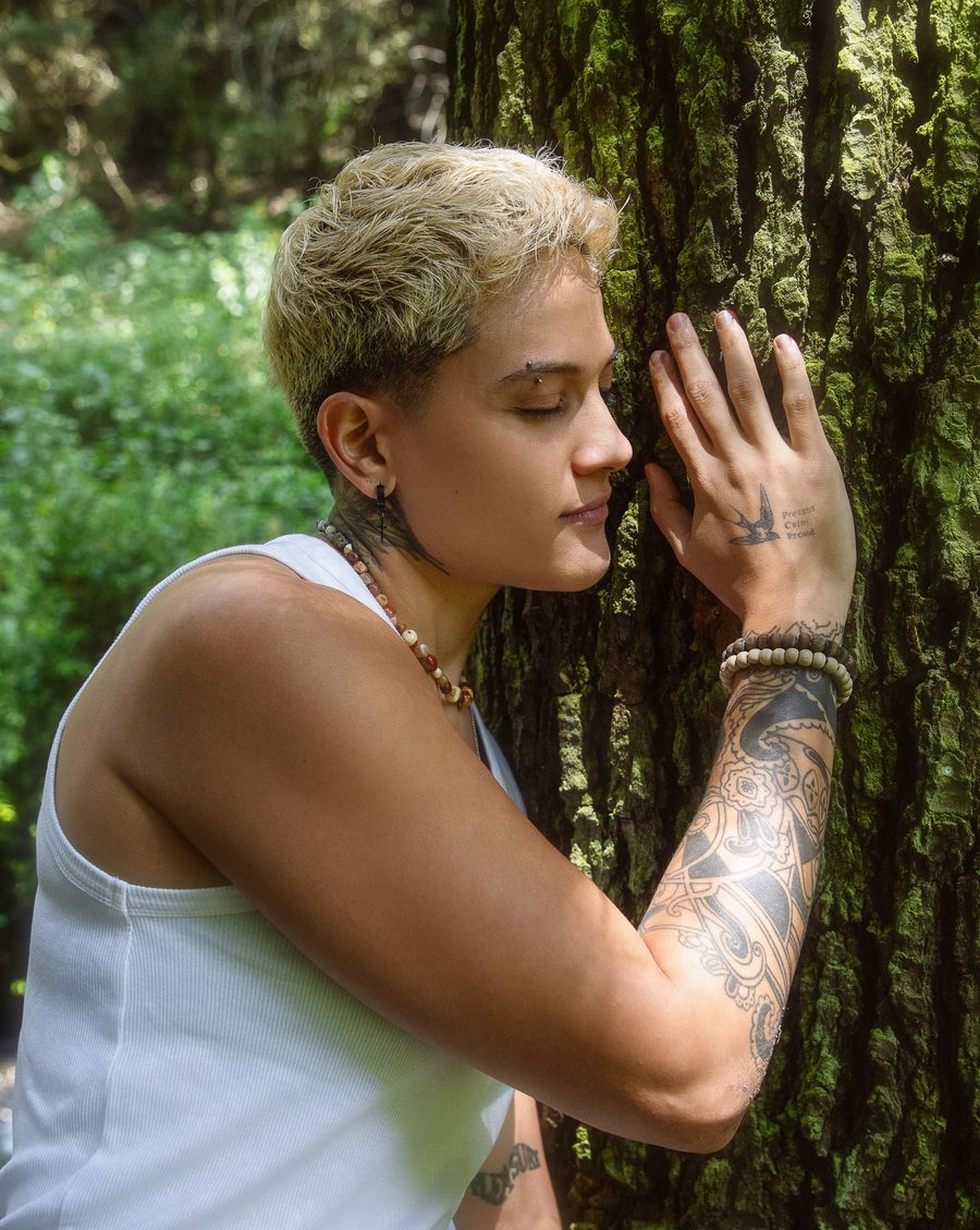 La Dra. Laura Salazar apoyada en el tronco de un árbol, con los ojos cerrados